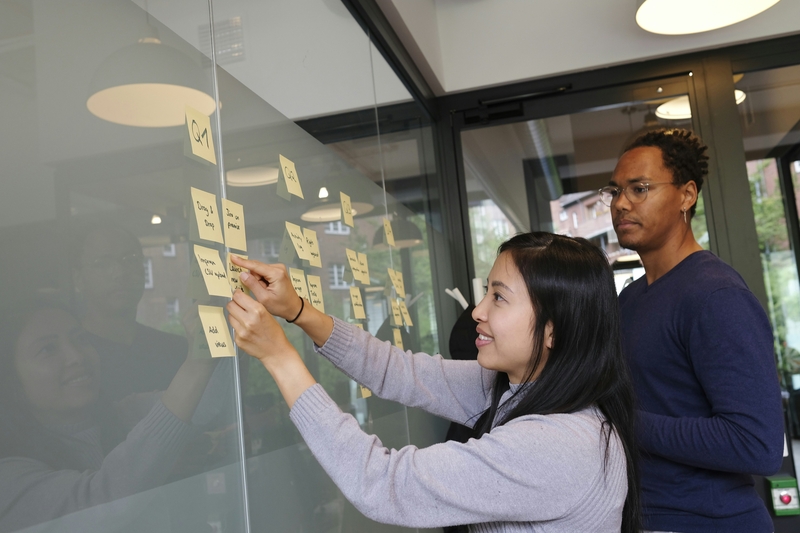 Two people looking at a Kanban board pinning notes relative to the service catalogue for ITSM case studies